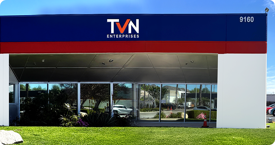 TVN Enterprises commercial building exterior with blue and red facade, glass entrance, and landscaped lawn.