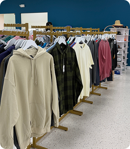 Custom branded polo shirts and t-shirts displayed on a clothing rack in a showroom setting.