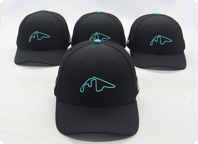 Four black trucker caps with blue embroidered logo displayed in a custom branded product showcase.