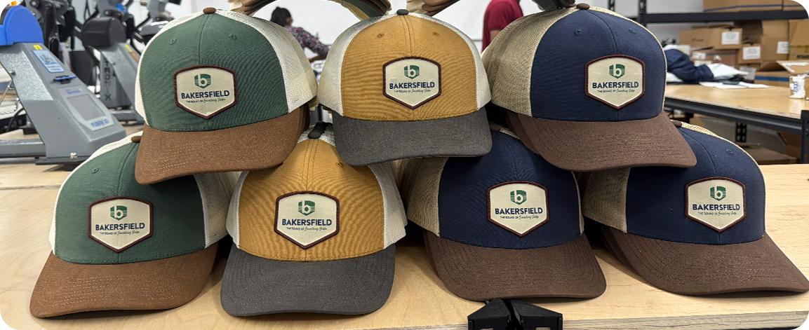 Custom trucker caps with leather patch logos displayed in multiple color options on a workshop table.