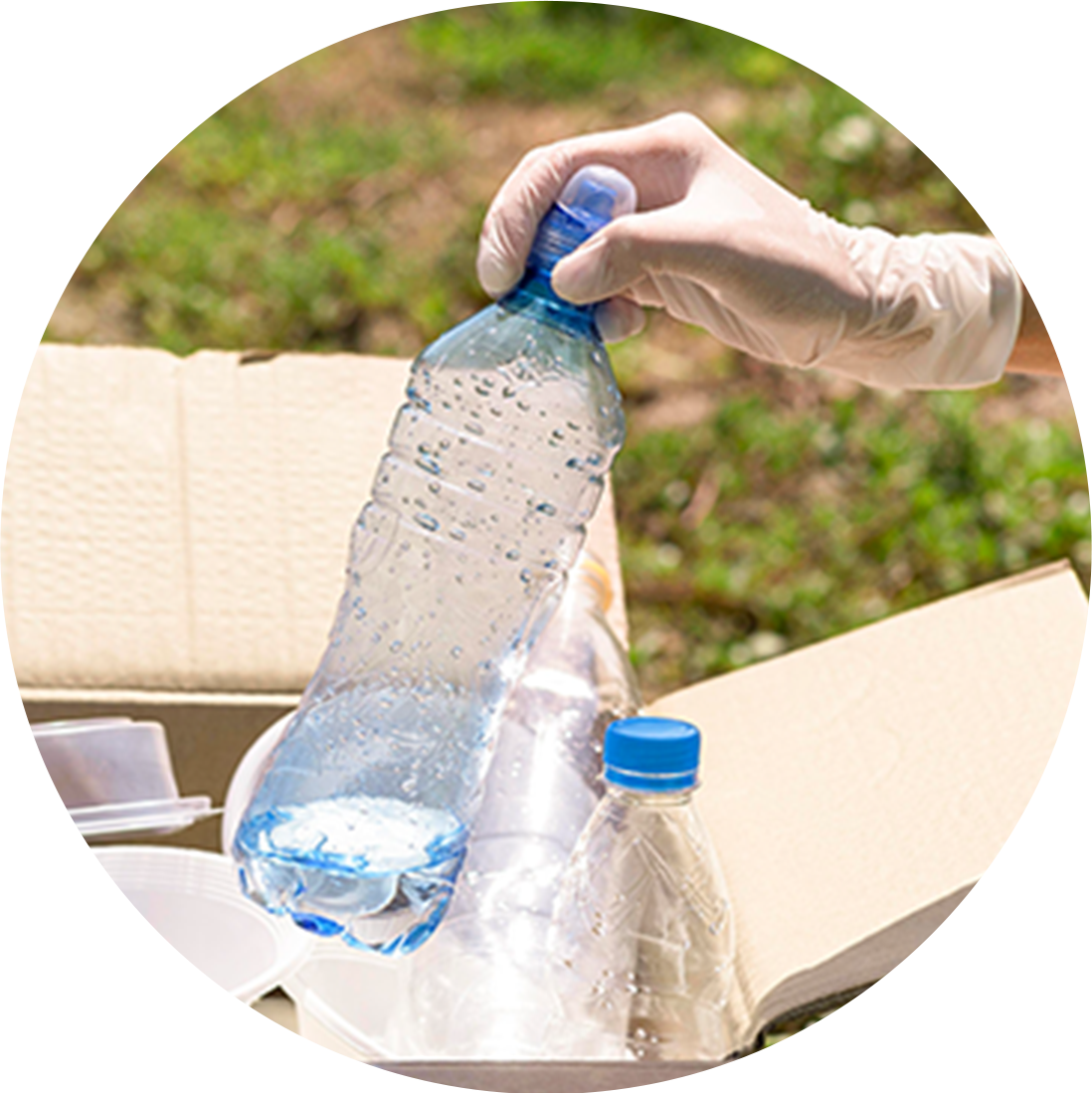 Gloved hand placing plastic bottles into a recycling bin to support waste reduction and environmental sustainability.