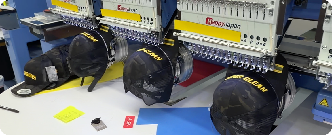 HappyJapan embroidery machines stitching custom logos on trucker caps in a professional production facility.